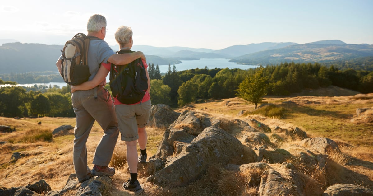 Older couple looking out at view of river, trees and hills in the distance