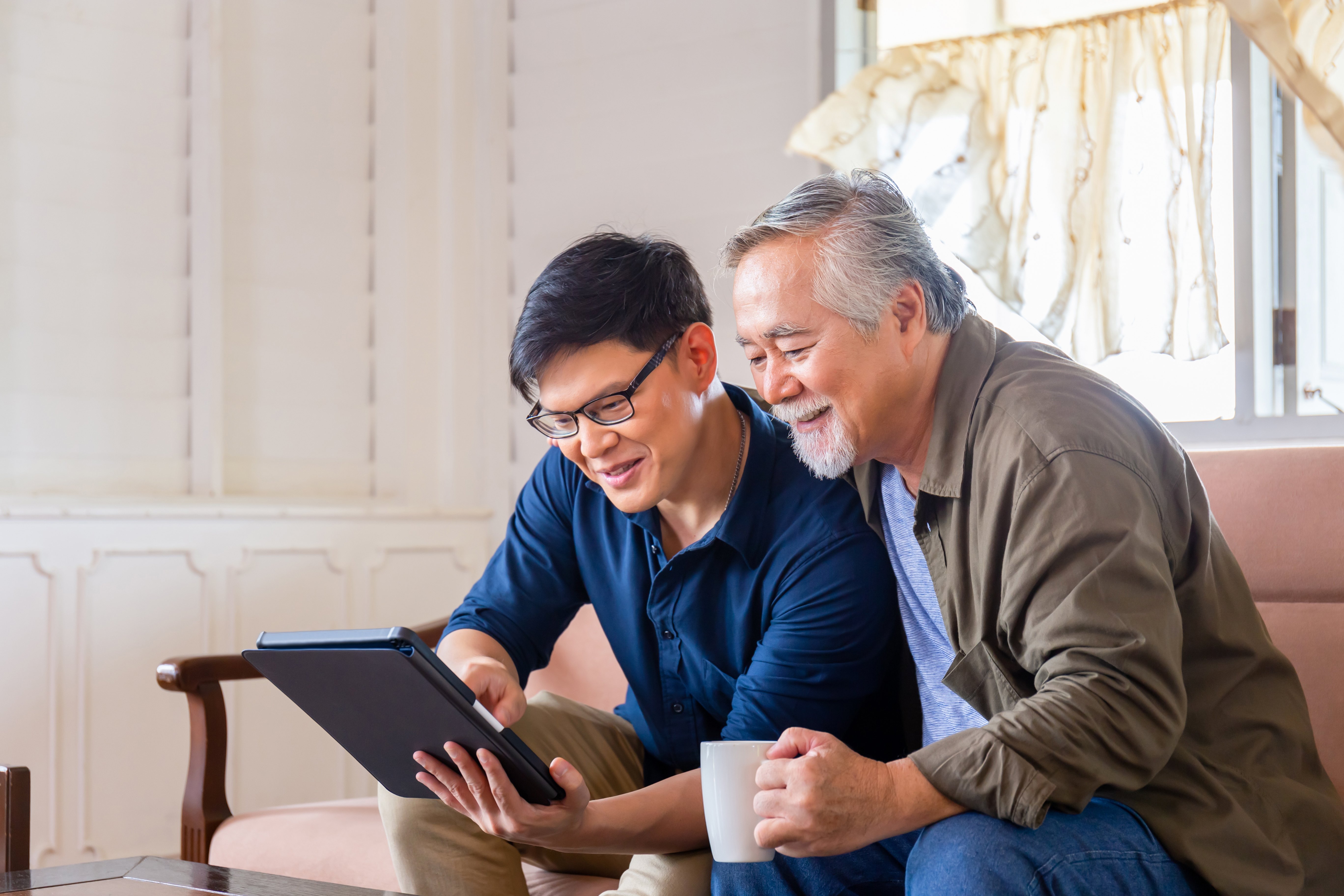 Elderly father and adult son looking at an iPad together