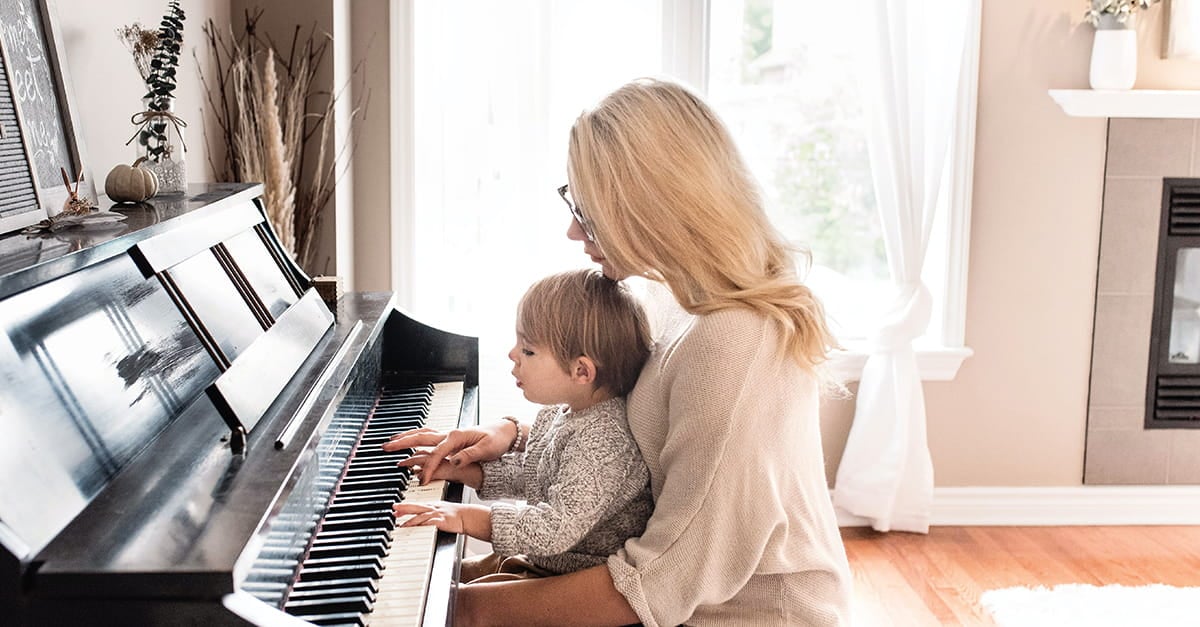 A mother holding her child while playing a paino.