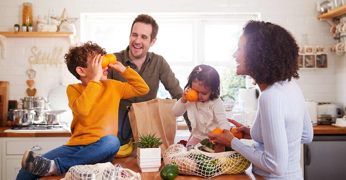A young family laughing while unloading groceries